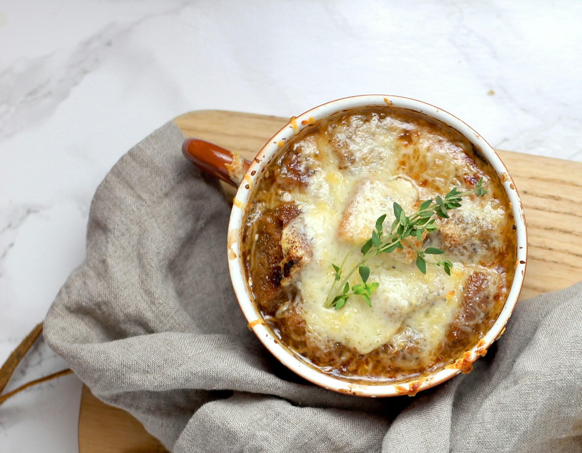 Bowl of French Onion Soup on a wooden plank by Sheri Silver on Unsplash